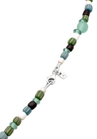 Perlekæde med grønne, blå, sorte og hvide glasperler, en sølvlås og et lille mærke. Skiftende teksturerede og glatte overflader.