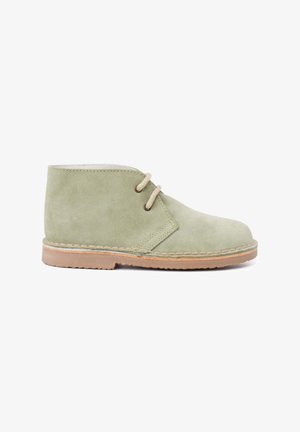 Bottines en suede vert avec une texture lisse, présentant un design simple, deux œillets pour les lacets et une semelle en caoutchouc brun clair.