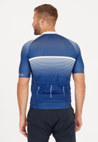 Sininen pyöräilypaita, jossa on valkoiset vaakasuorat raidat, lyhyet hihat ja tiukka leikkaus. Sisältää vetoketjullisen takataskun ja hengittävää kangasta.