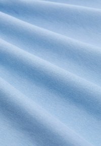 Himmelblauer Stoff mit glatter Textur, der subtile gerippte Muster und Falten zeigt und seine weiche und flexible Natur demonstriert.