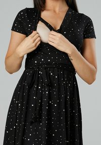 Black dress with short sleeves featuring gold star patterns, a wrap design, and a tied waist. The fabric appears soft and stretchy.