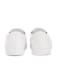 Paire de baskets basses blanches vues de dos, avec tissu cousu et semelles signées Tommy Hilfiger.
