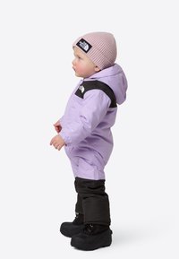 Světle fialová zateplená kombinéza na sníh s černými doplňky, s kapucí, elastickými manžetami a černými botami. Růžová žebrovaná čepice s logem.