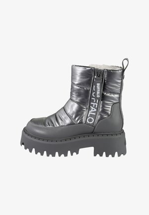 Szary, wyściełany botek na kostkę o błyszczącym wykończeniu. Posiada masywną podeszwę, kontrastujący czarny akcent na pięcie, zamek błyskawiczny po boku oraz detal z logo.