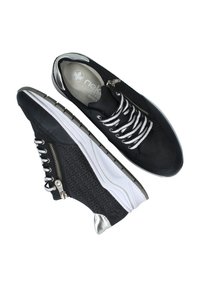 Schwarze Sneakers mit weißen Schnürsenkeln, strukturiertem Stoff, metallischen Akzenten, seitlichem Reißverschluss und einer dicken weißen Sohle mit grauem Profil.