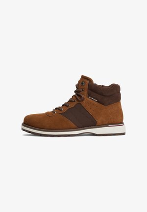 Brauner Wildleder- und Stoff-Schnürstiefel mit gepolstertem Kragen und weißer Gummisohle mit einem dünnen roten und blauen Streifen.