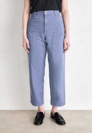 Light blue high-waisted jeans with a straight-leg cut, featuring front pockets and a button closure. Paired with black loafers.