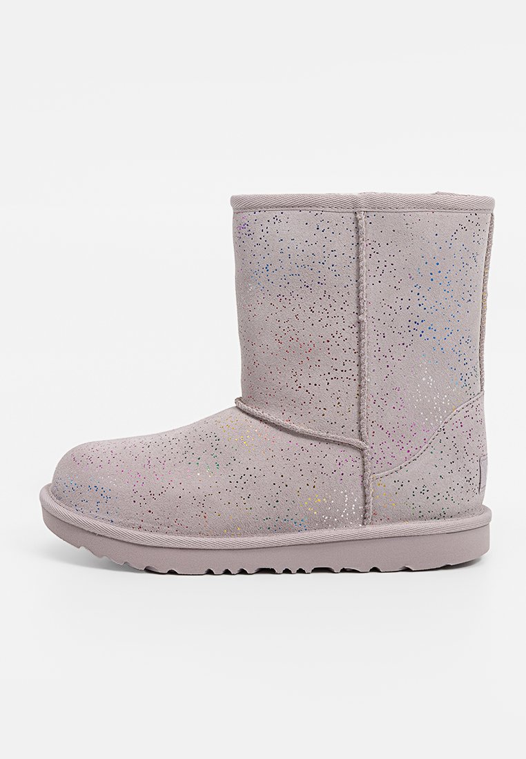 Grijze suede enkellaars met een lichte glinsterpatroon, ronde neus, gestikte accenten en een getextureerde rubberen zool. De hoogte bedraagt tot halverwege het kalf.