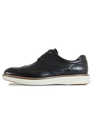 Black leather brogue dress shoe with wingtip perforations and white rubber sole, lace-up closure, and low heel.