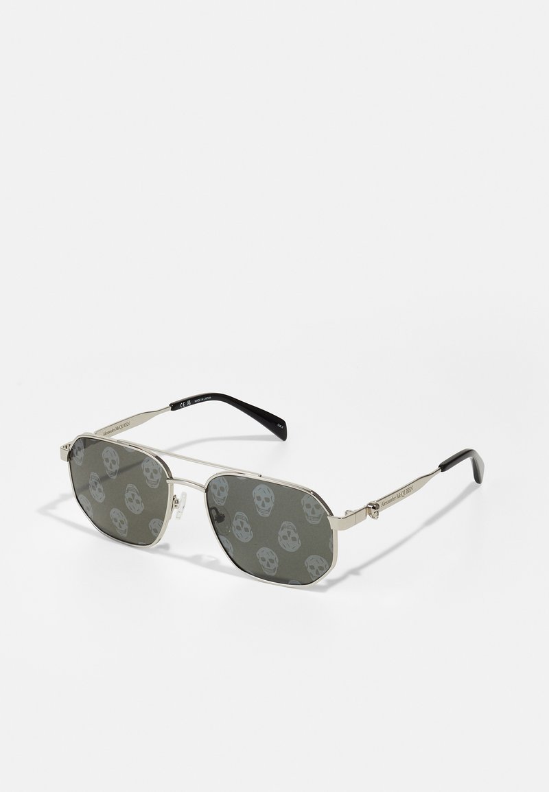 Metal sunglasses with a rectangular shape, grey lenses featuring repeated skull patterns, and black temple arms. Silver-tone frame accents.