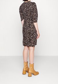 Svart klänning med leopardmönster, trekvartslånga ärmar, figursydd midja och knälängd. Matchad med tanfärgade ankelfoppor med kraftig klack.