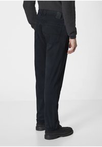 Black, straight-leg trousers made of a soft fabric. Features two rear pockets and a branded patch on the waistband. Smooth texture.