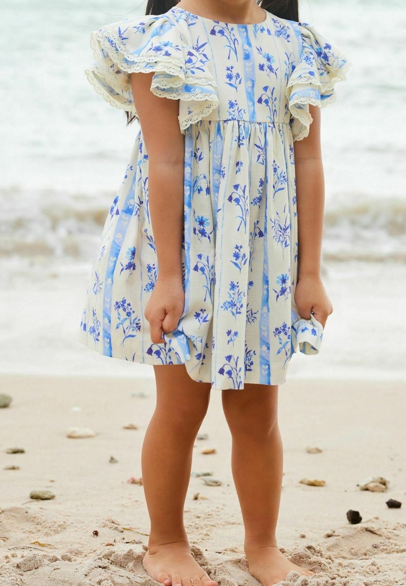 Robe florale bleu clair avec de courtes manches volantées et un bord en dentelle. Le motif présente des rayures verticales et des fleurs bleues éparpillées sur un fond beige.