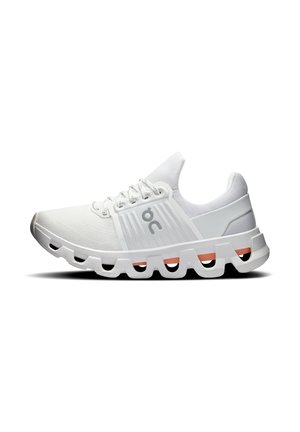 Zapatilla deportiva blanca con suela acolchada que presenta huecos rectangulares huecos y detalles naranjas, parte superior de punto y diseño con cordones.