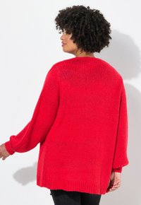 Maglione rosso oversize lavorato a maglia con vestibilità ampia, maniche a pipistrello e orlo a coste. Tessuto texturizzato con un aspetto morbido e lavorazione aperta.