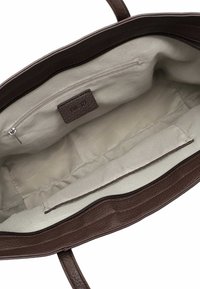 Borsa tote in pelle marrone con fodera in tessuto crema, dotata di una tasca con zip e un'etichetta. Texture morbida e design minimalista.