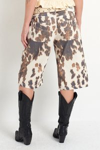 Džínové šortky s leopardím vzorem a béžovým podkladem, se zadními kapsami, doplněné černými kovbojskými botami.