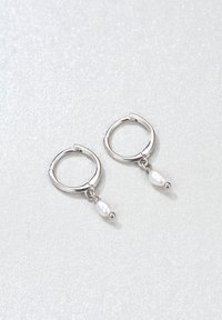 Orecchini a cerchio in argento con finitura lucida, caratterizzati da perle bianche pendenti e piccoli dettagli a forma di sfera in argento.