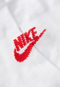 Hvit tekstil med en brodert rød Nike-logo med buede accenter og en lett hevet tekstur.