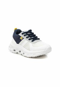 Zapatillas deportivas blancas y marinas con paneles de malla, tela texturizada, suela gruesa y acento amarillo en el talón.