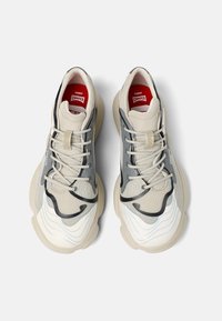 Beige and gray sneakers with wave patterns, textured mesh fabric, and cushioned rubber soles. Red insole with "KARST CAMPER" logo.