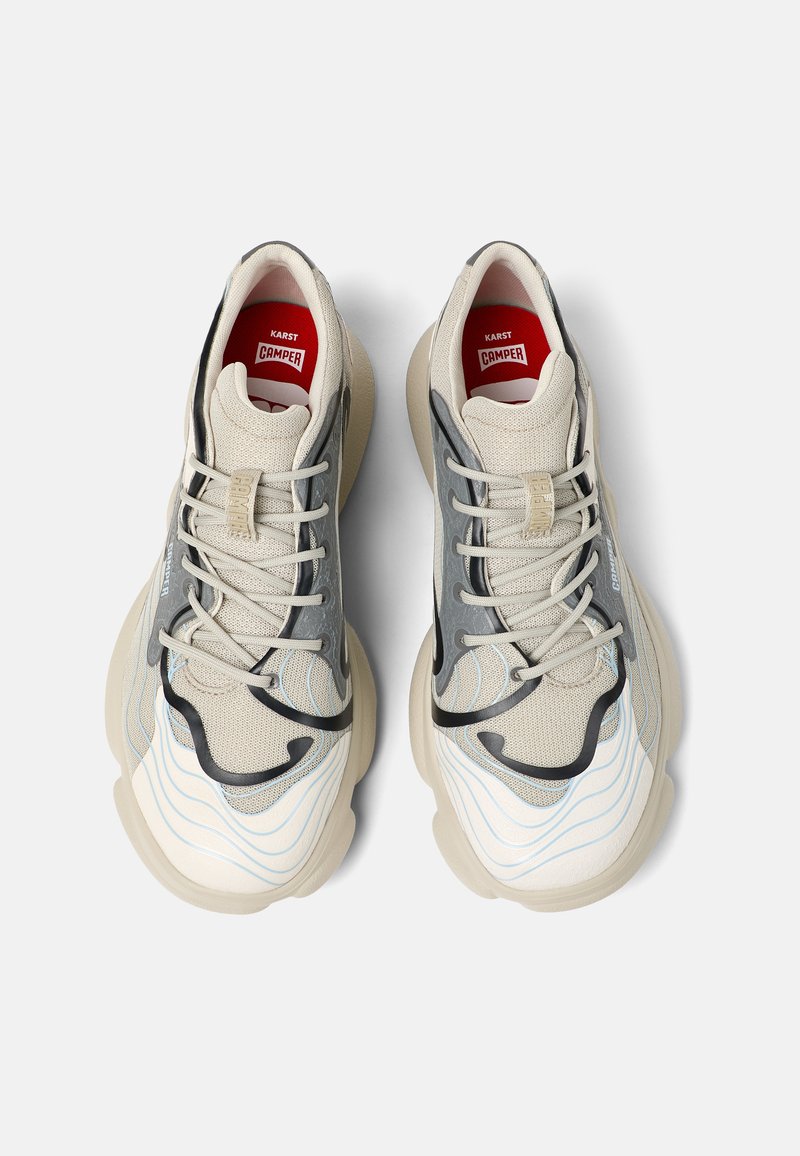 Beżowe i szare sneakersy z falistymi wzorami, teksturowaną siateczką oraz miękkimi gumowymi podeszwami. Czerwona wkładka z logo "KARST CAMPER".