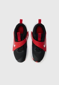 Chaussures de sport rouges et noires avec une empeigne texturée, une sangle réglable et des accents blancs. Présente un col et une languette rembourrés.