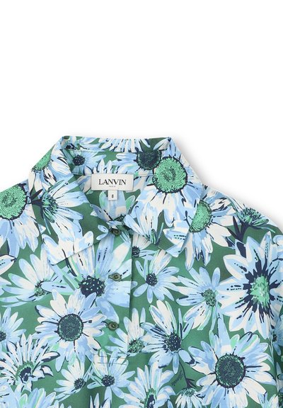 Chemise à manches courtes en tissu vert ornée d'un imprimé floral avec de grandes marguerites bleues et blanches, au centre noir, et un col classique.