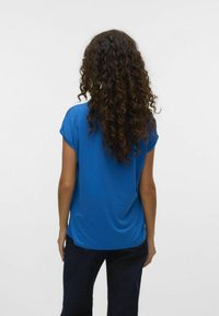 Blauw kortemouwtop van een soepele, lichte stof. Heeft een relaxte pasvorm en een ronde halslijn, weergegeven van achteren met donkere spijkerbroek.