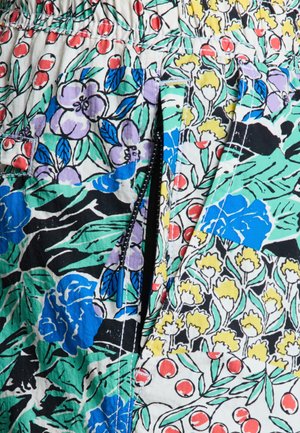 Tkani s cvjetnim uzorkom koja sadrži crvene bobice, ljubičaste cvjetove i zelene listove. Uključuje bočni patentni zatvarač s plavim povlačnim trakama.
