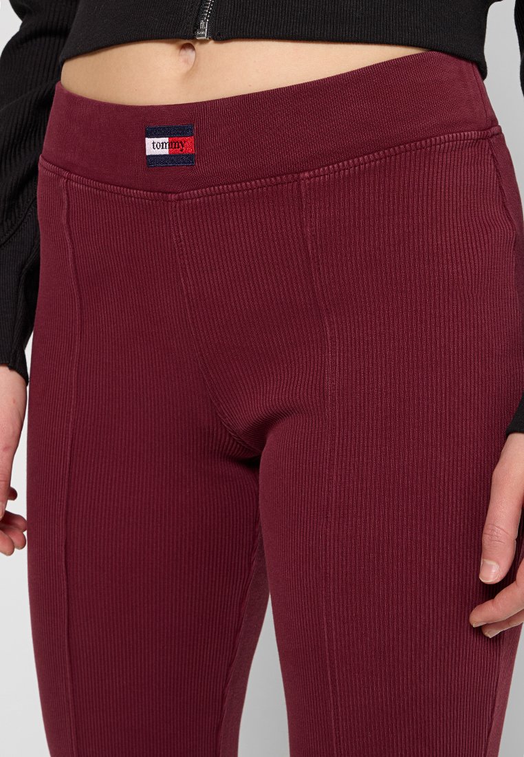 Bordeaux ribbelleggings met een brede elastische tailleband en een klein logo-embleem. De stof lijkt rekbaar en aansluitend.
