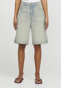 Svetlo modri jeans kratki hlače bermuda z srednjim pasom, ohlapnim krojem in strganim robom. Ima tradicionalne sprednje žepke in subtilne izbledelosti.