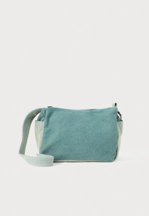 Rektangulær crossbody-veske laget av teksturert sjøgrønn stoff med skulderstropp. Har glidelås og avrundede hjørner.