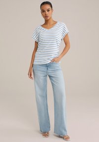Striped V-neck t-shirt in white and blue, paired with light blue denim wide-leg jeans. Sandals with thin straps complete the look.