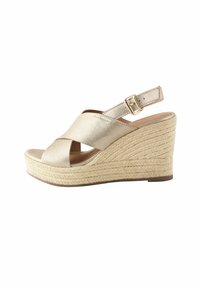 Gouden leren wedge sandalen met kruislingse banden, een verstelbare enkelband en een met jute omhulde platformzool.