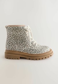 Botas de tobillo con estampado de leopardo, fabricadas en un tejido texturizado, con acentos beige, cordones blancos y una suela de goma gruesa en color marrón claro. Presentan ojales de metal y costuras.