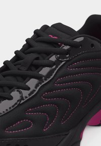 Μαύρο αθλητικό παπούτσι με ροζ ραφές και λεπτομέρειες, ανώτερο μέρος από δίχτυ, γυαλιστερές επικαλύψεις και σφιχτά δεμένα μαύρα κορδόνια.