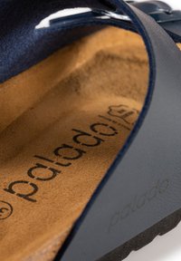 Mörkblå sandal med en inredning som liknar mocka, utrustad med en texturerad gummisula och en synlig logotyp på fotbädden.