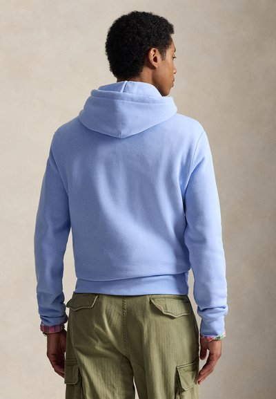 Φούτερ με κουκούλα σε ανοιχτό γαλάζιο χρώμα, με μεγάλη, απαλή κουκούλα, ριμπ μανσέτες και κοντό σχέδιο, συνδυασμένο με χακί cargo παντελόνι με τσέπες στα πλευρά.