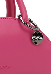 Roze faux leren handtas met een ronde vorm, een gladde textuur en een zilveren ronde tag met de merknaam "Buffalo."