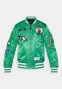 Jachetă bomber din satin verde, cu logo-uri Boston Celtics, accente brodate, manșete și tiv rayures, și mai multe patch-uri pe mâneci.
