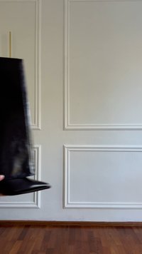 Stivale alla caviglia in pelle nera con punta appuntita e tacco basso e curvo. Texture liscia, design minimalista e silhouette elegante.