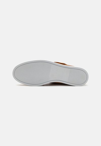 Brown sandal featuring a thick gray rubber sole with a textured pattern. The upper has a smooth leather finish and a wide strap.