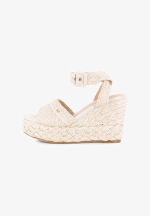 Sandalia de cuña con diseño de paja trenzada, color beige, puntera abierta y tira al tobillo con hebilla, que presenta una suela de plataforma texturizada.