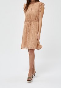 Šaty v broskvové barvě s krátkými rukávy, volánkovým výstřihem a stahovacími pasem; mají malé hnědé puntíky a lehkou, splývavou látku.