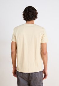 Beige bomulds t-shirt med rund hals, korte ærmer og regular fit. Stoffet er glat, uden synlige mønstre eller detaljer.