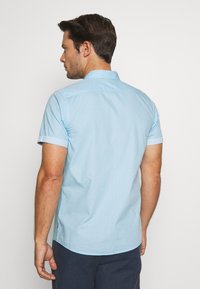 Helles blaues kurzärmeliges Hemd mit einem strukturierten Muster, Button-down-Kragen und umgeschlagenen Manschetten, aus leichtem Stoff gefertigt.