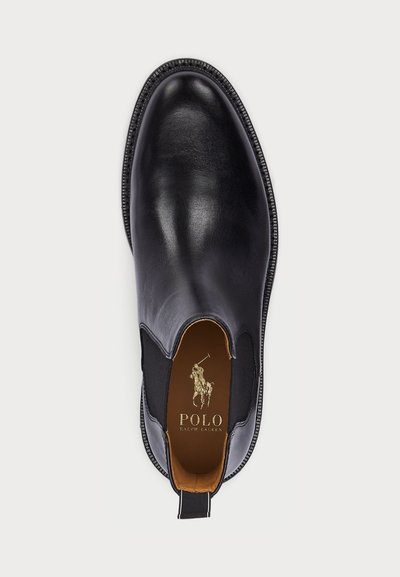 Black leather dress shoe with elastic side panels, round toe, and contrast stitching. Features a tan insole and a gold logo inside.