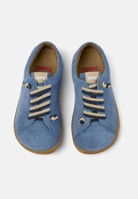 Modré semišové boty s kulatou špičkou, béžovými šňůrkami a gumovými podrážkami. Obsahují viditelné švy a štítek s logem Camper na jazyku.