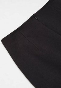 Jupe noire à texture lisse, dotée d'une fermeture éclair latérale discrète et de deux poches sur les côtés. Design simple et structuré avec une silhouette épurée.